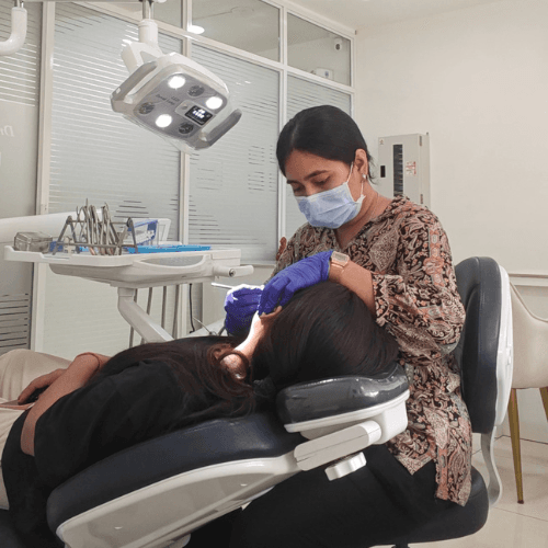 A dentist performing a gentle dental check-up and teeth cleaning on a child patient in a clean, modern clinic